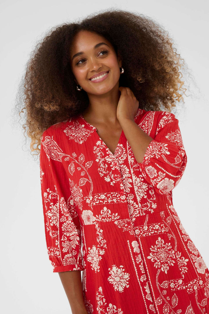 Femme portant une Robe Bia midi imprimée à manches trois-quarts avec encolure en V, coupe fluide en rouge décoratif, sourire éclatant.