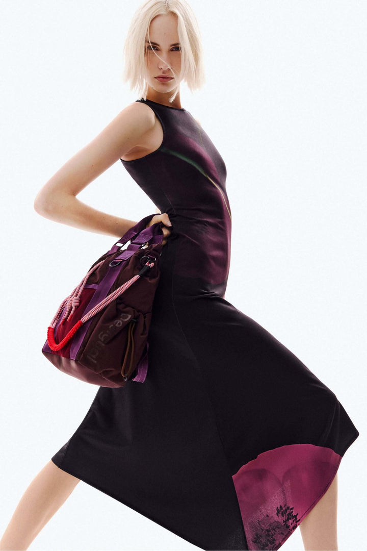 Robe asymétrique coquelicot avec imprimé floral artistique, sans manches et coupe évasée, portant un sac à main. Mode élégante et moderne.
