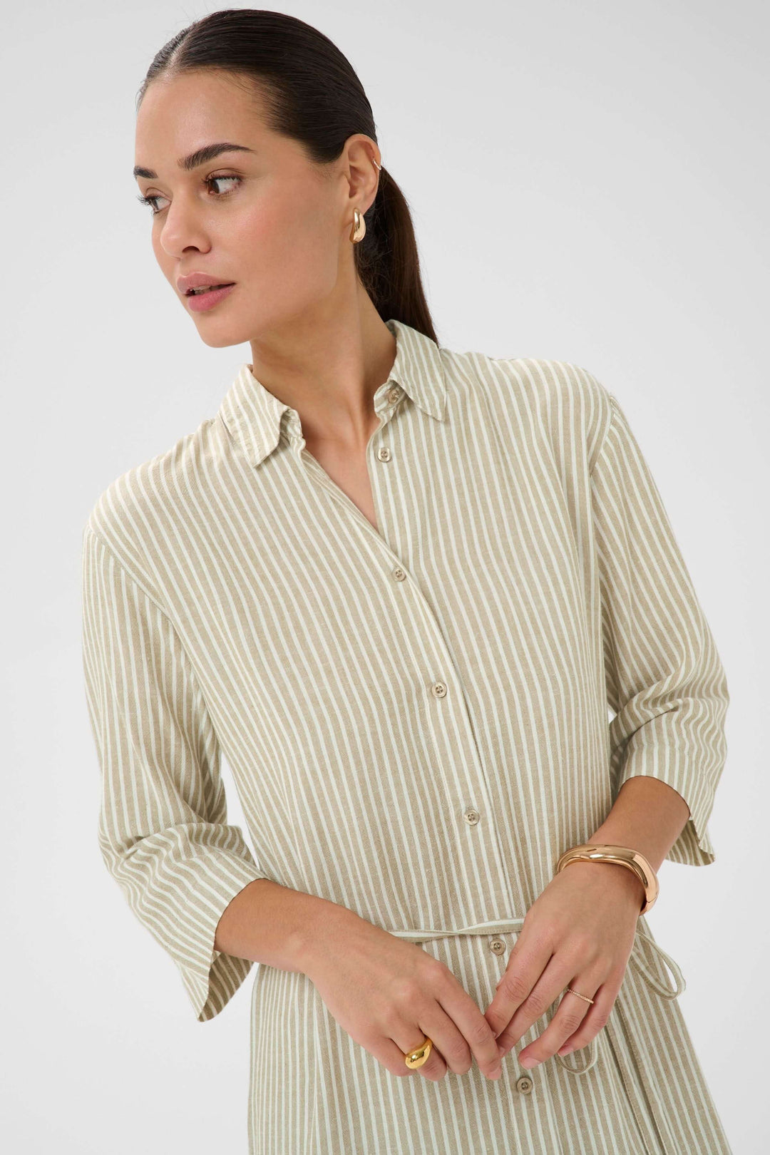 Femme portant la Robe chemise Milia à rayures avec ceinture, col classique et manches trois-quarts.