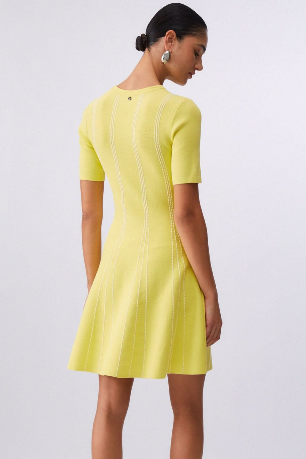 Robe courte en maille à motif rayé en couleur jaune vue de dos avec manches courtes et coupe évasée féminine.