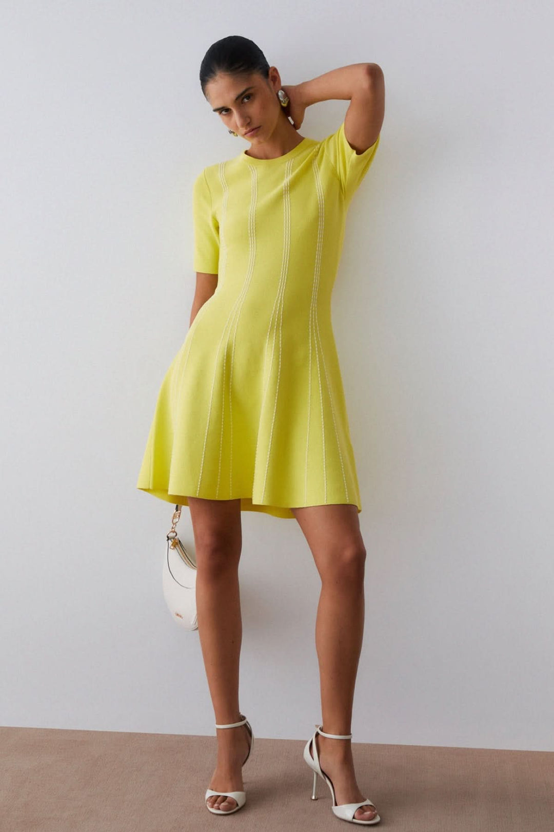Robe courte en maille à motif rayé jaune avec une silhouette féminine et moderne, idéale pour un look quotidien ou une occasion habillée.