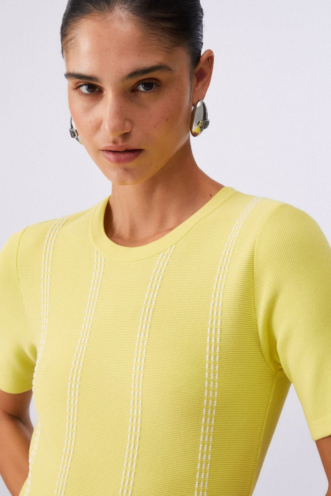 Femme portant une robe courte en maille à motif rayé jaune avec manches courtes.