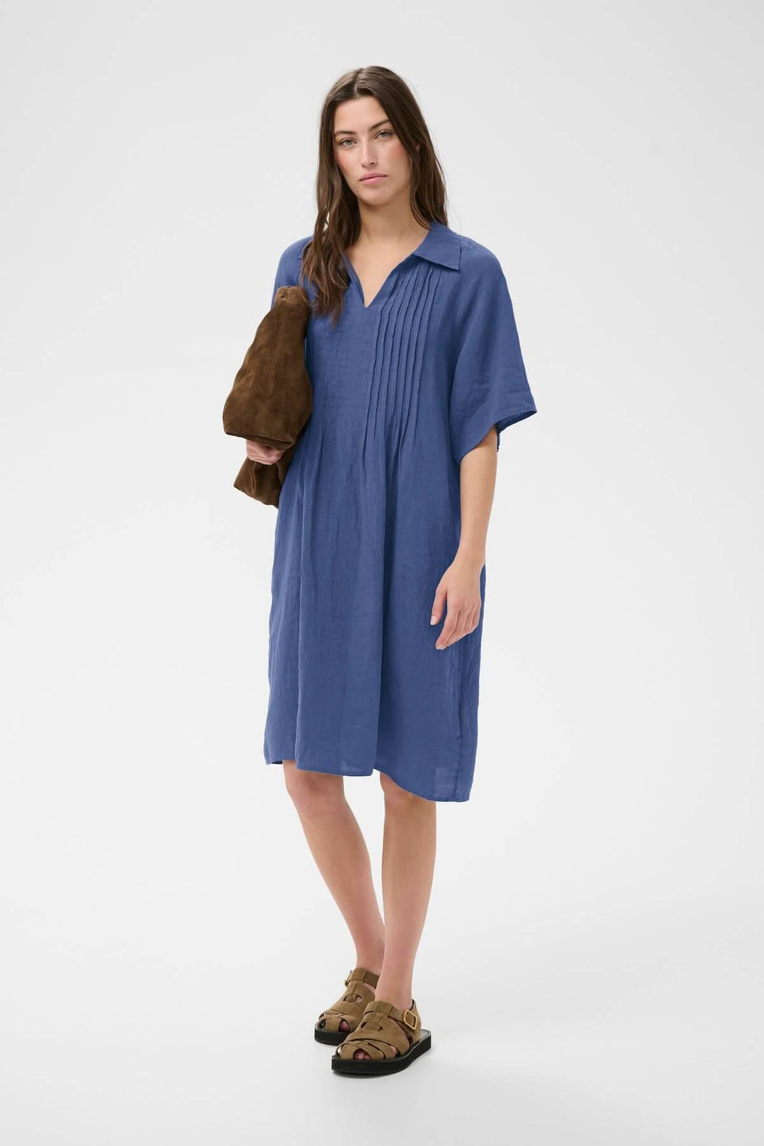 Femme portant la "Robe en lin Ayla" bleue avec détails plissés, coupe droite et style décontracté, idéale pour toute occasion.