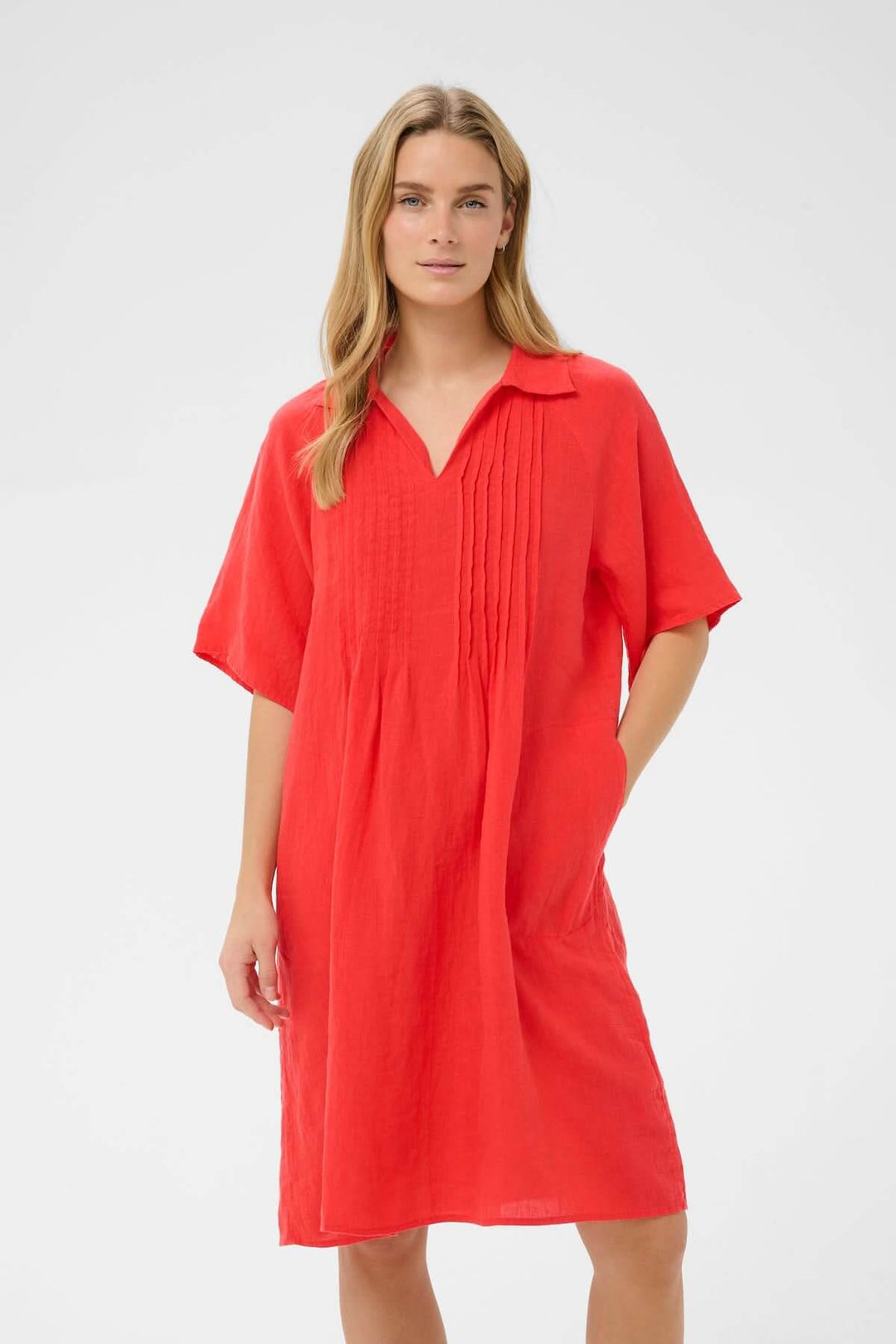 Femme portant la Robe en lin Ayla rouge avec coupe droite et détails plissés élégants, longueur au genou, col souple.