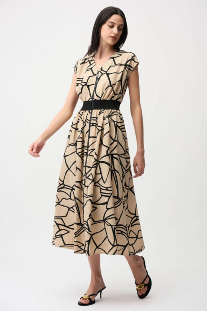 Femme portant une robe imprimée à taille marquée avec imprimé graphique audacieux, taille soulignée et jupe ample, vue de face.