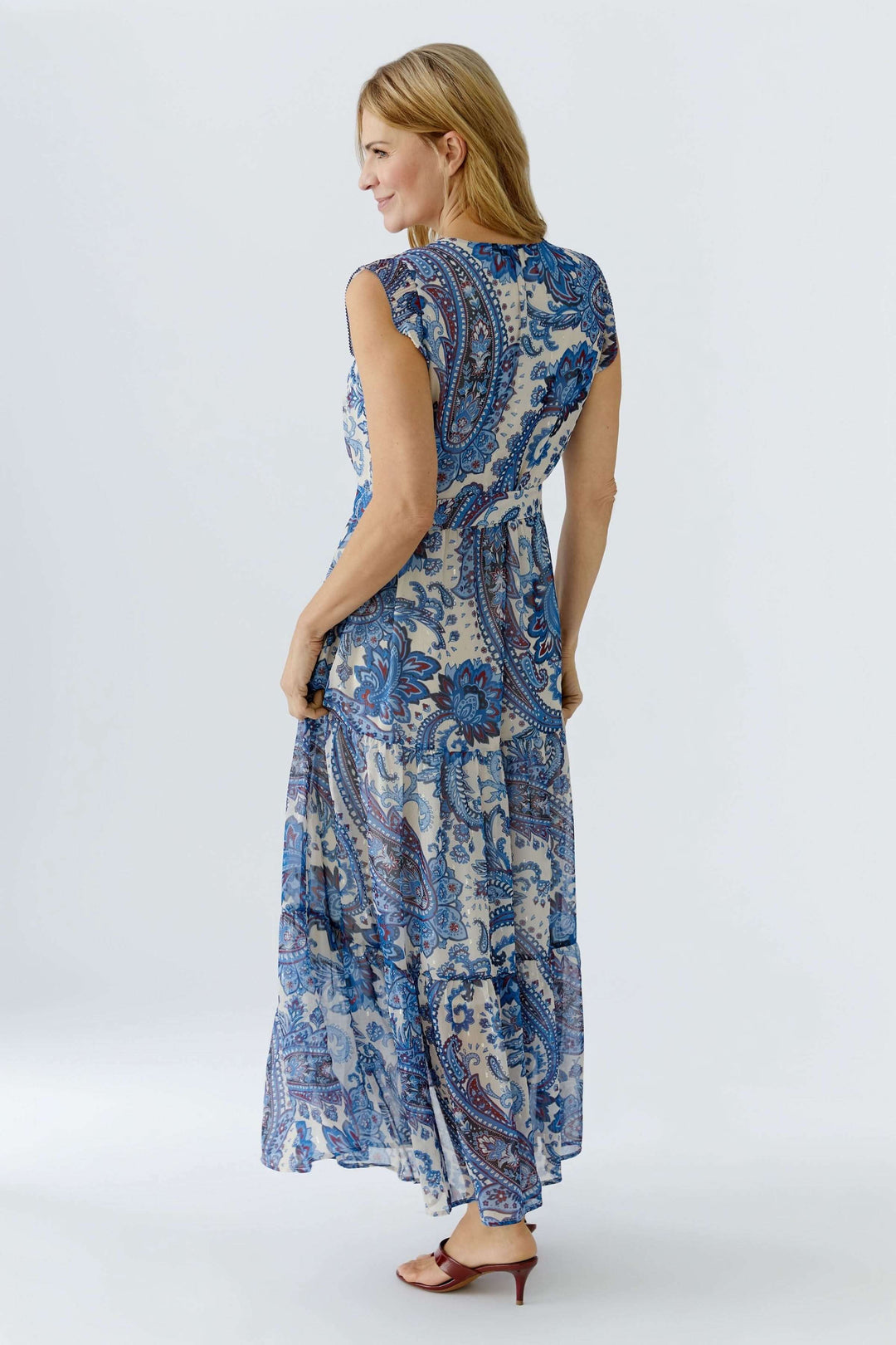 Femme portant une robe longue à imprimé paisley, dos tourné, soulignant la coupe fluide et élégante idéale pour les journées ensoleillées.