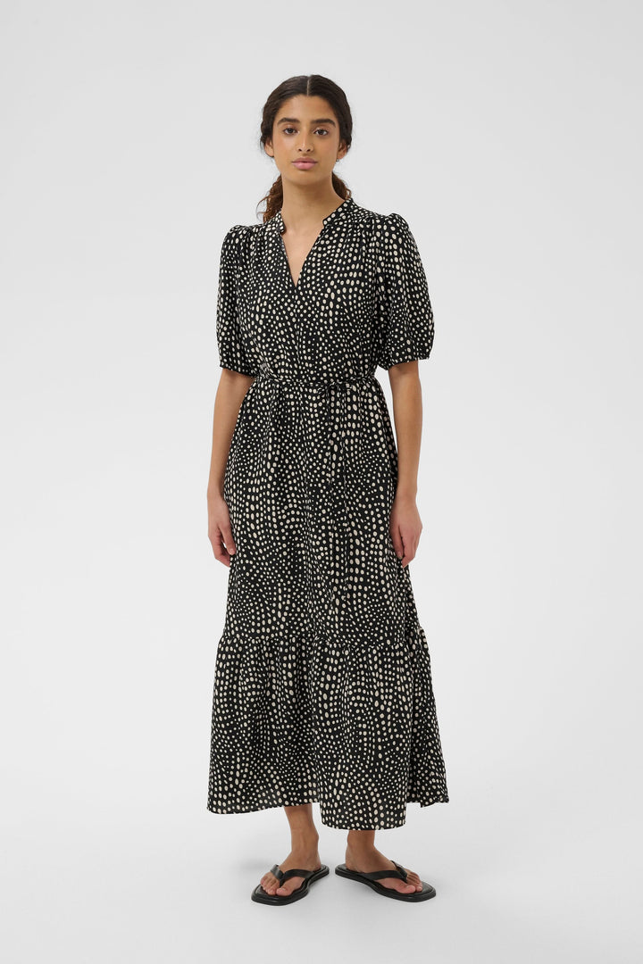 Femme portant une robe longue imprimée à taille ceinturée avec manches bouffantes et encolure en V pour un look élégant.