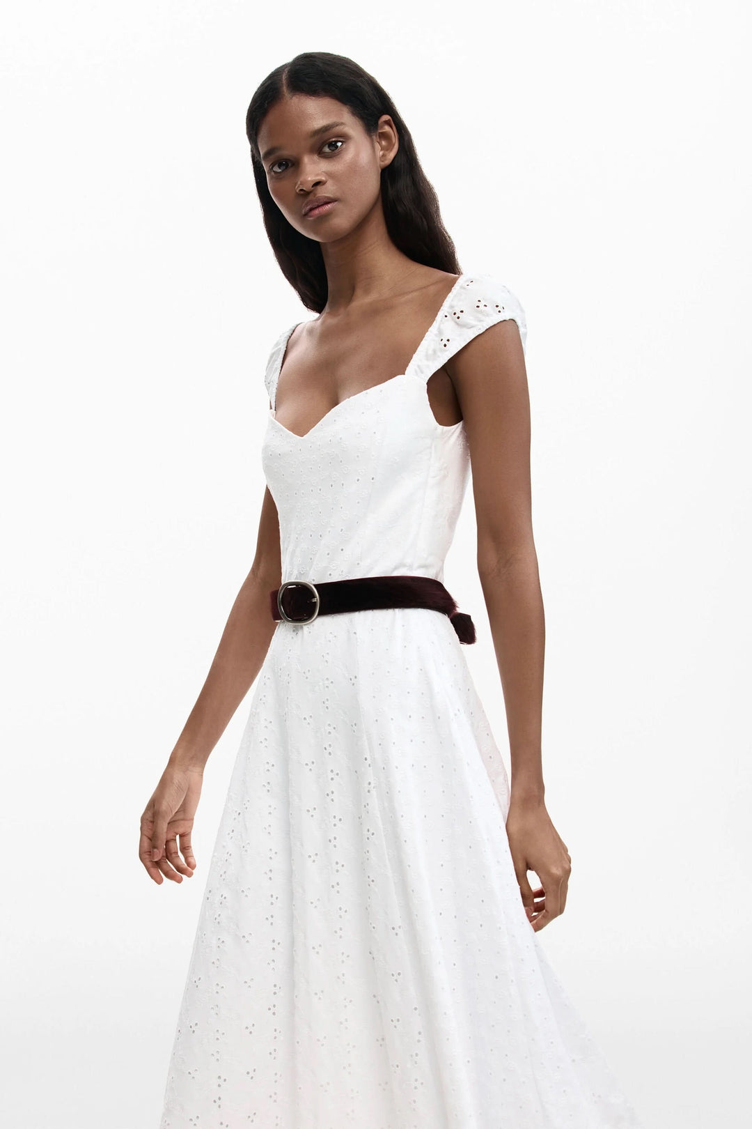 Femme portant une robe midi brodée blanche avec encolure cœur et bretelles larges, idéale pour l&