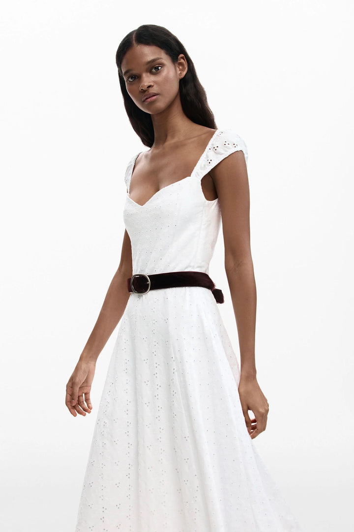 Femme portant une robe midi brodée blanche avec encolure cœur et bretelles larges, idéale pour l&