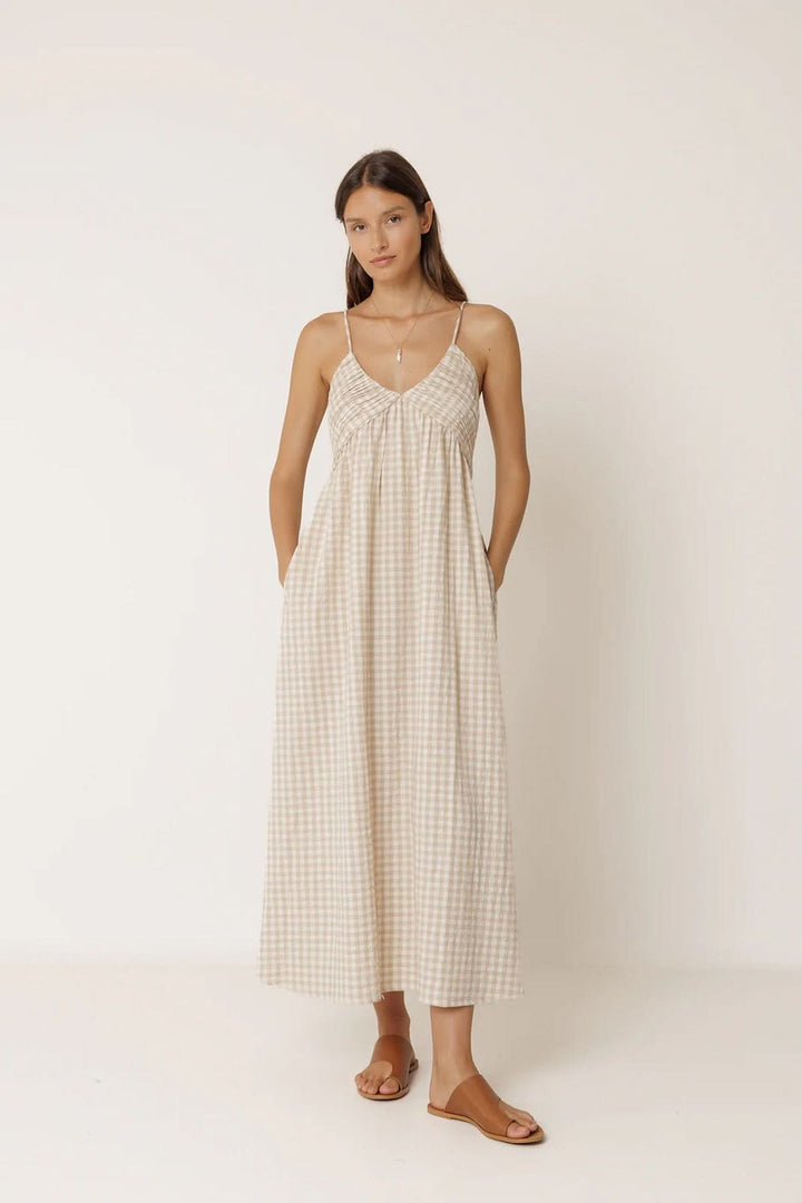 Femme portant une robe midi à motif vichy avec fines bretelles et encolure en V, élégante et fluide pour journées ensoleillées.