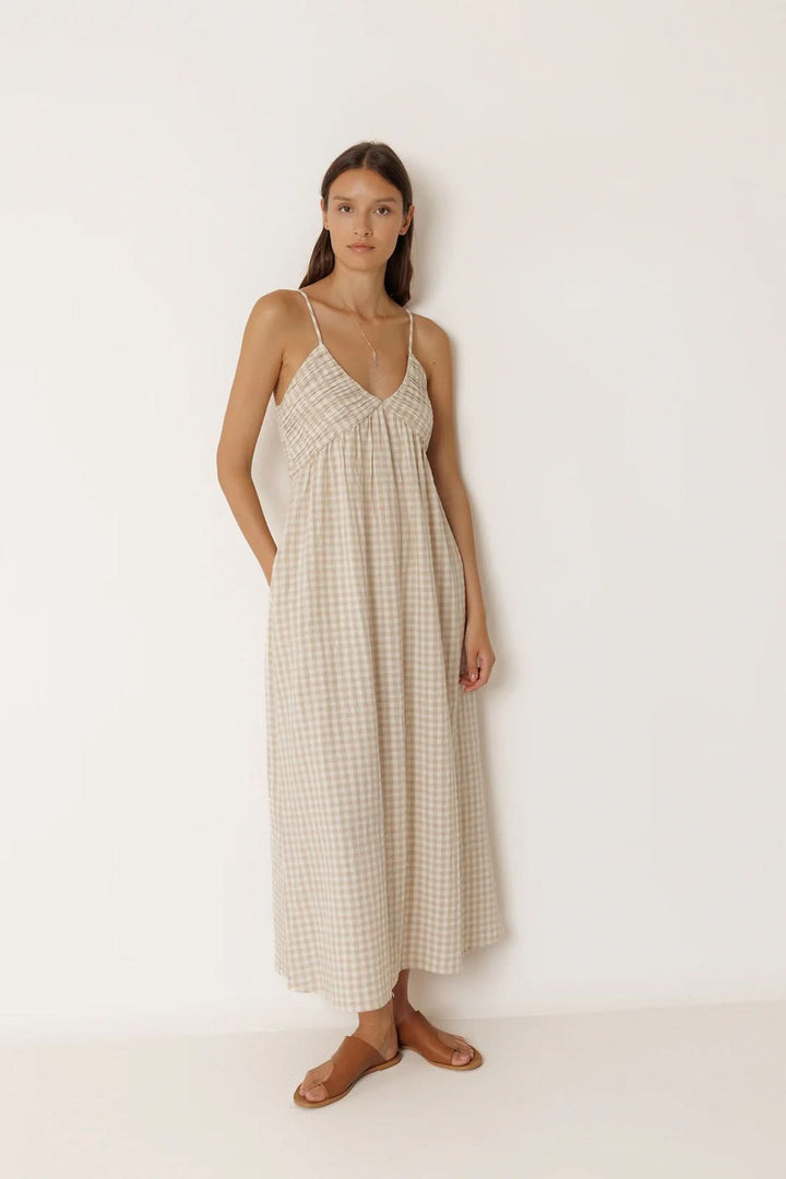 Femme portant une robe midi à motif vichy avec fines bretelles et encolure en V, élégante et fluide pour les journées ensoleillées.