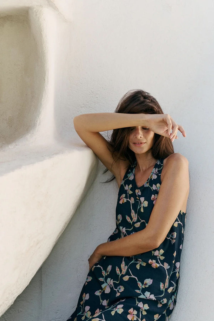 Robe midi sans manches à imprimé floral portée par une femme, mettant en valeur une allure estivale et féminine.