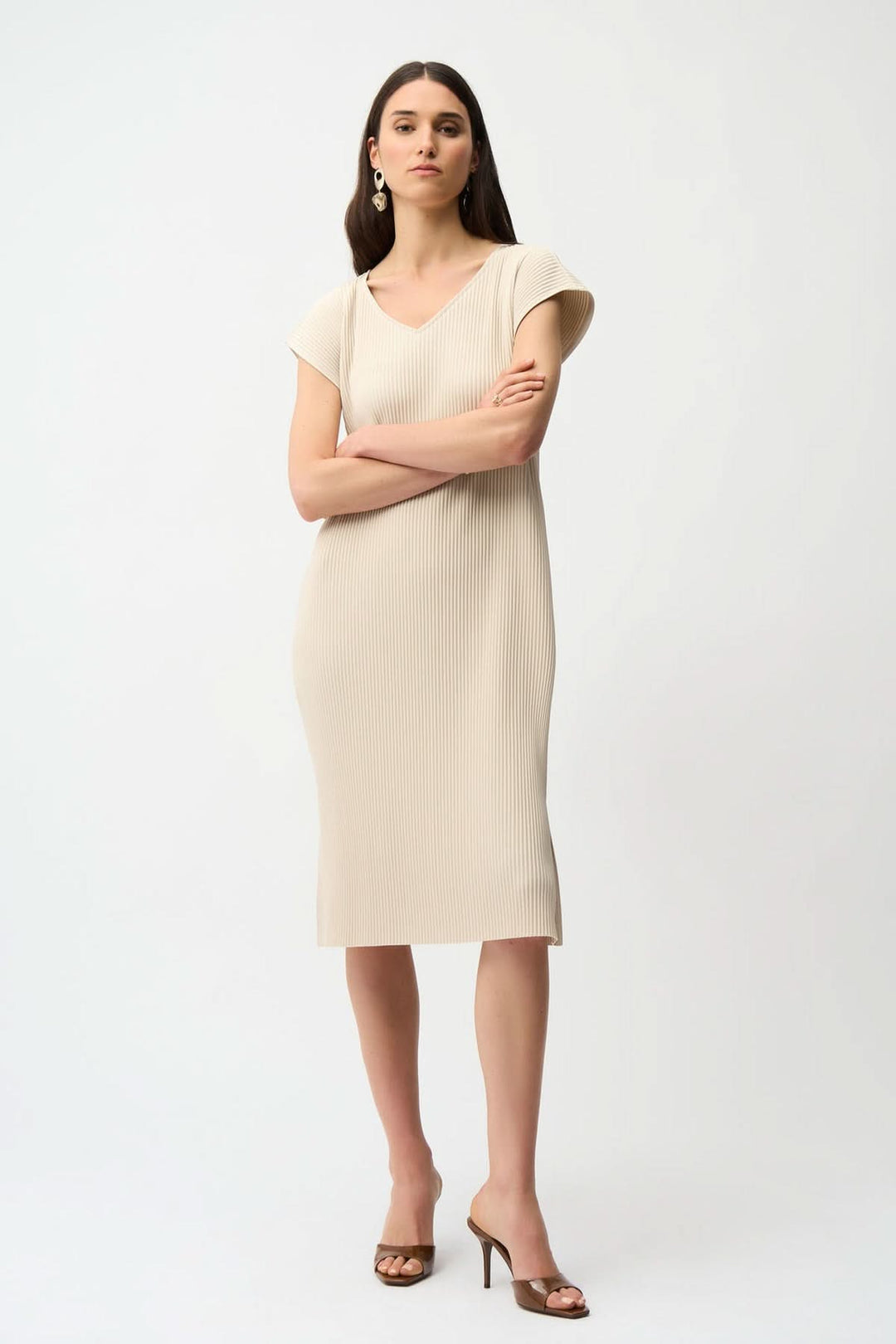 Femme portant une robe plissée avec poches, mi-longue, à texture côtelée et décolleté en V, idéale pour les occasions variées.