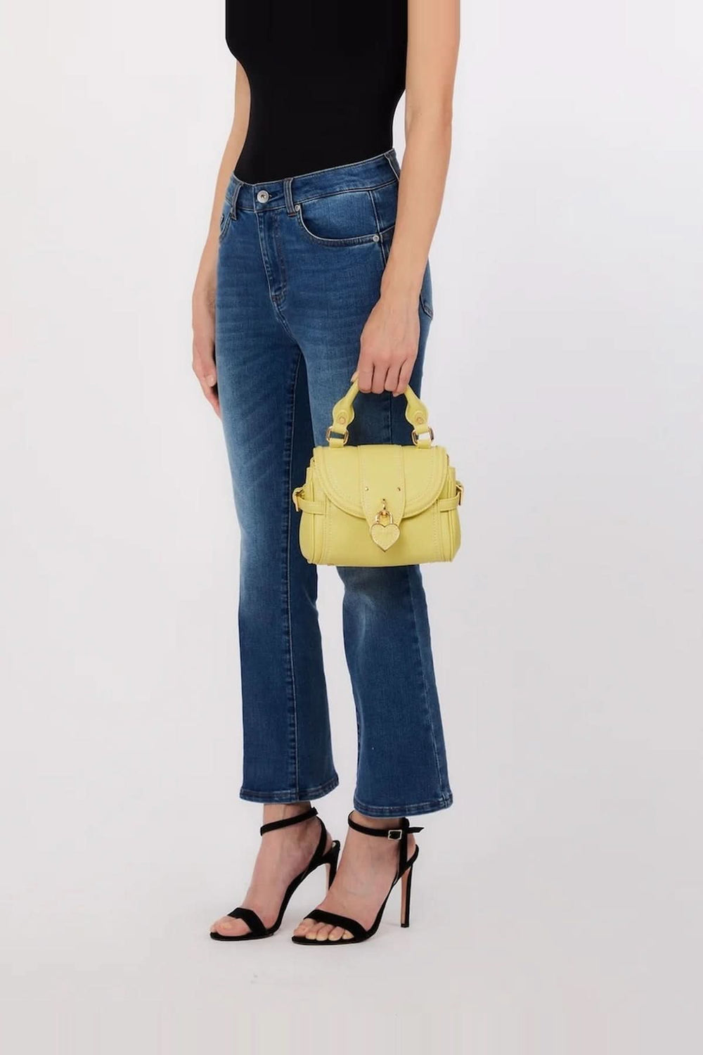Femme tenant un sac à main structuré avec breloque cœur, élégant et compact, parfait pour le quotidien.