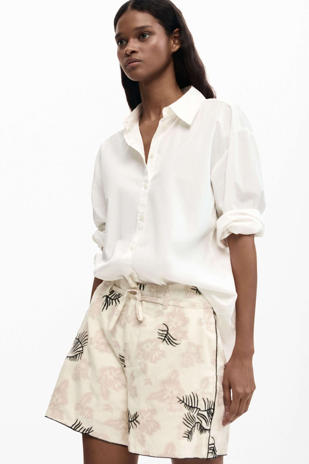 Femme portant un short fluide à imprimé brodé avec motif élégant et poches latérales, idéal pour un look décontracté et raffiné.