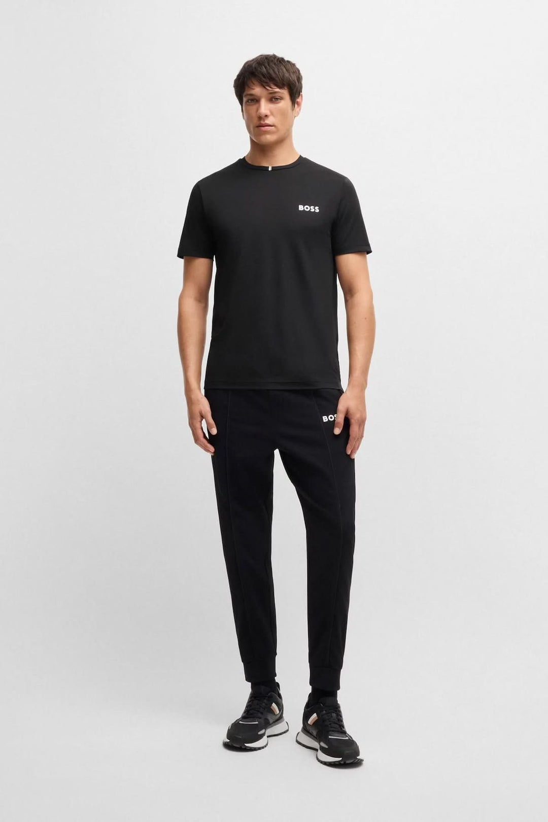 Homme portant un t-shirt BOSS épuré avec logo discret et pantalon noir, style casual chic.