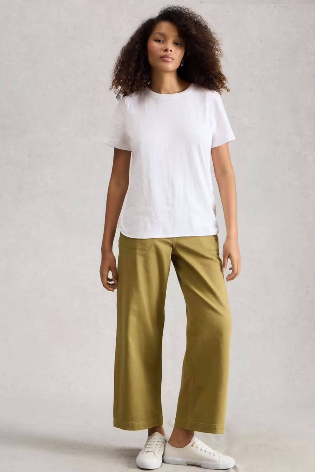 Femme portant le T-shirt Clara à col rond et manches courtes, style minimaliste et confortable.
