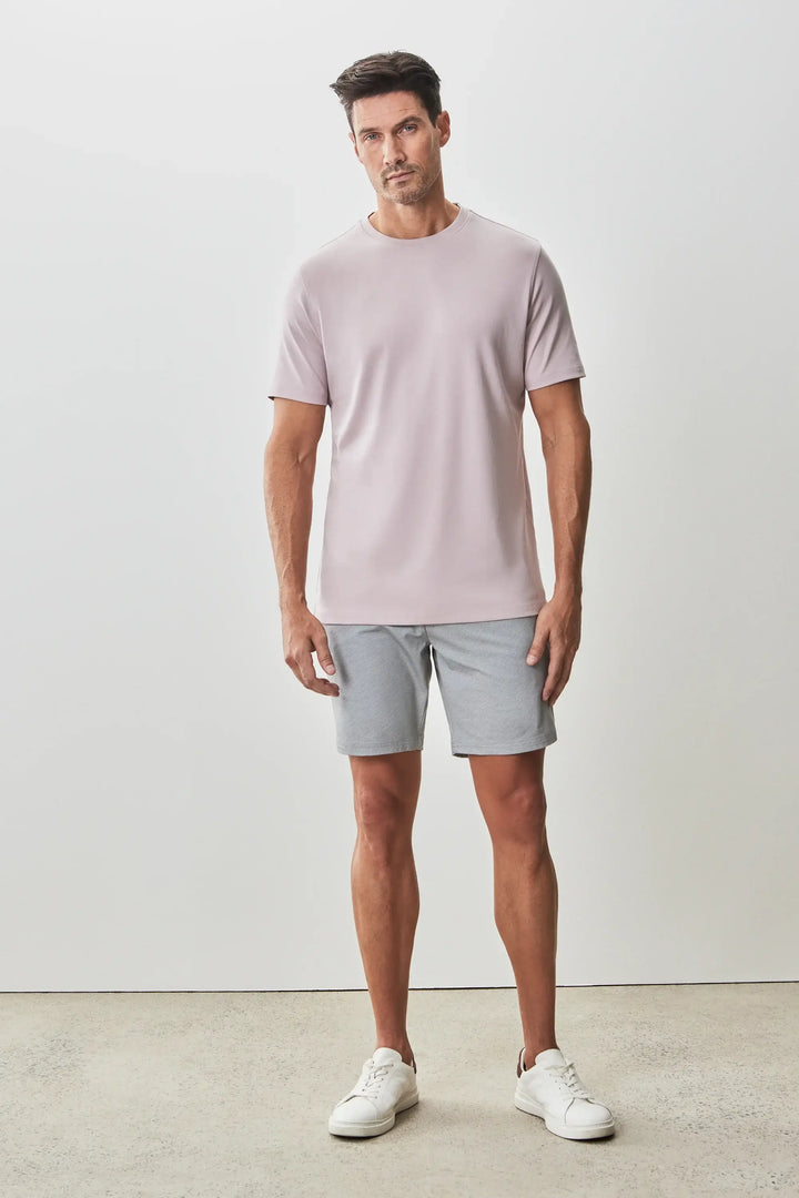 Homme portant un t-shirt Georgia à manches courtes, coloris léger, avec un short gris et des sneakers blanches.