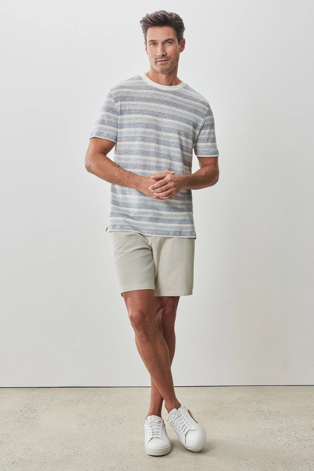 Homme portant un t-shirt à rayures texturées et un short clair pour un look estival décontracté.