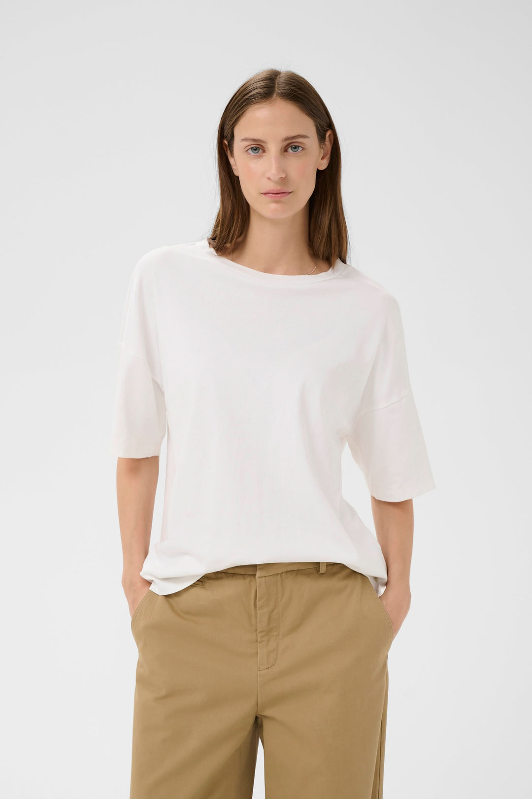 Femme portant le T-shirt Sophie fluide à nouer au dos, blanc, manches courtes larges, encolure ronde, coupe ample pour un confort absolu.