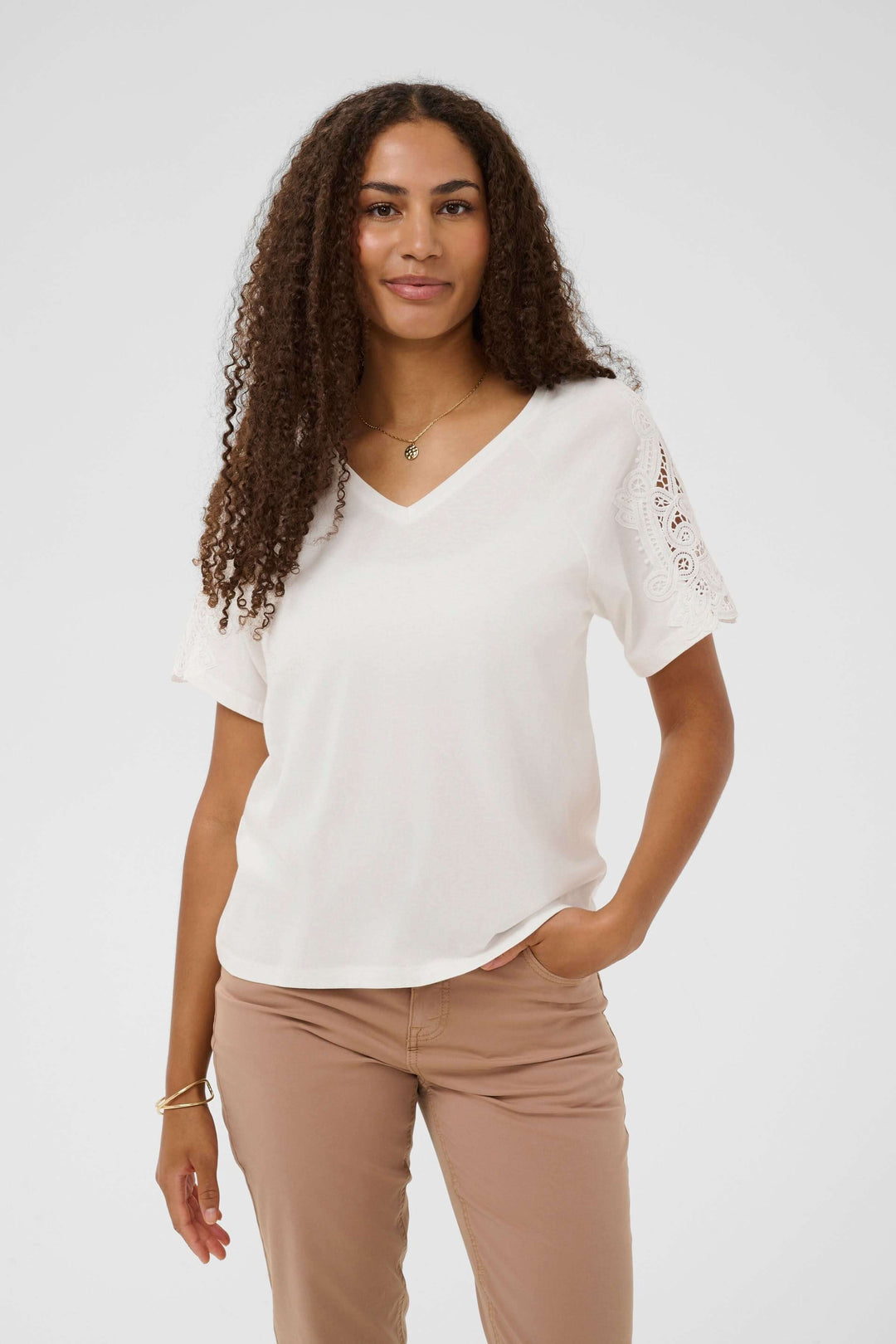 Femme portant un T-shirt Suny à manches courtes avec dentelle, encolure en V, blanc, avec manches ornées de dentelle, coupe droite élégante.
