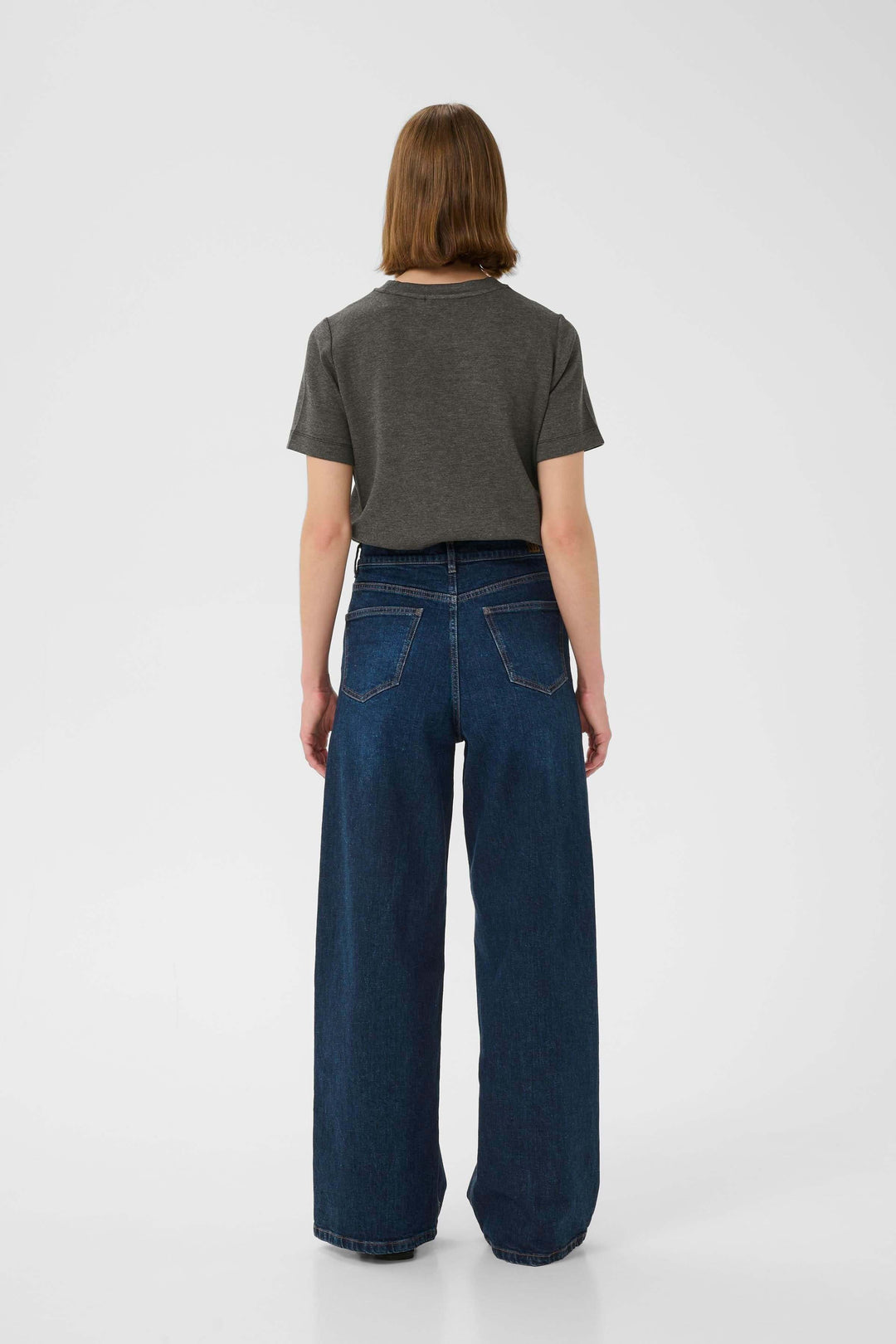 Femme de dos portant un t-shirt gris et un jean large, montrant un style décontracté et élégant.