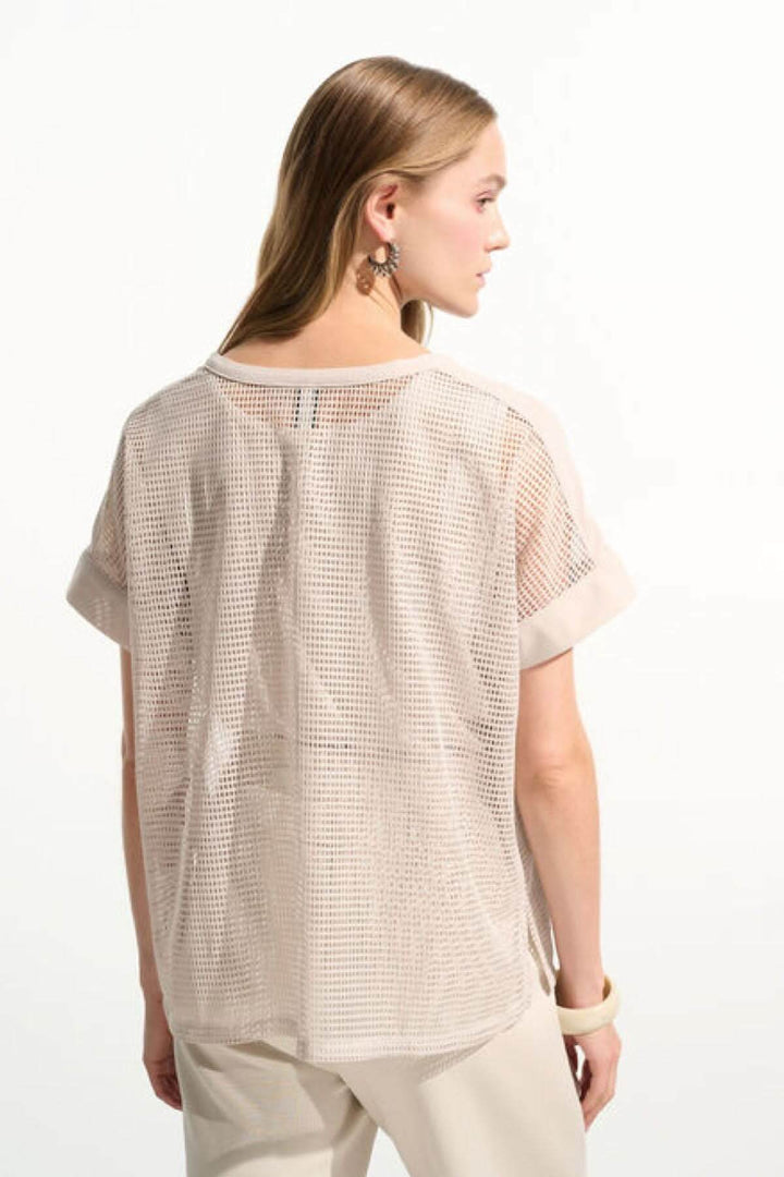 Femme portant un T-shirt ajouré fluide moderne avec manches courtes à revers, maille légère, idéal pour superposition été.