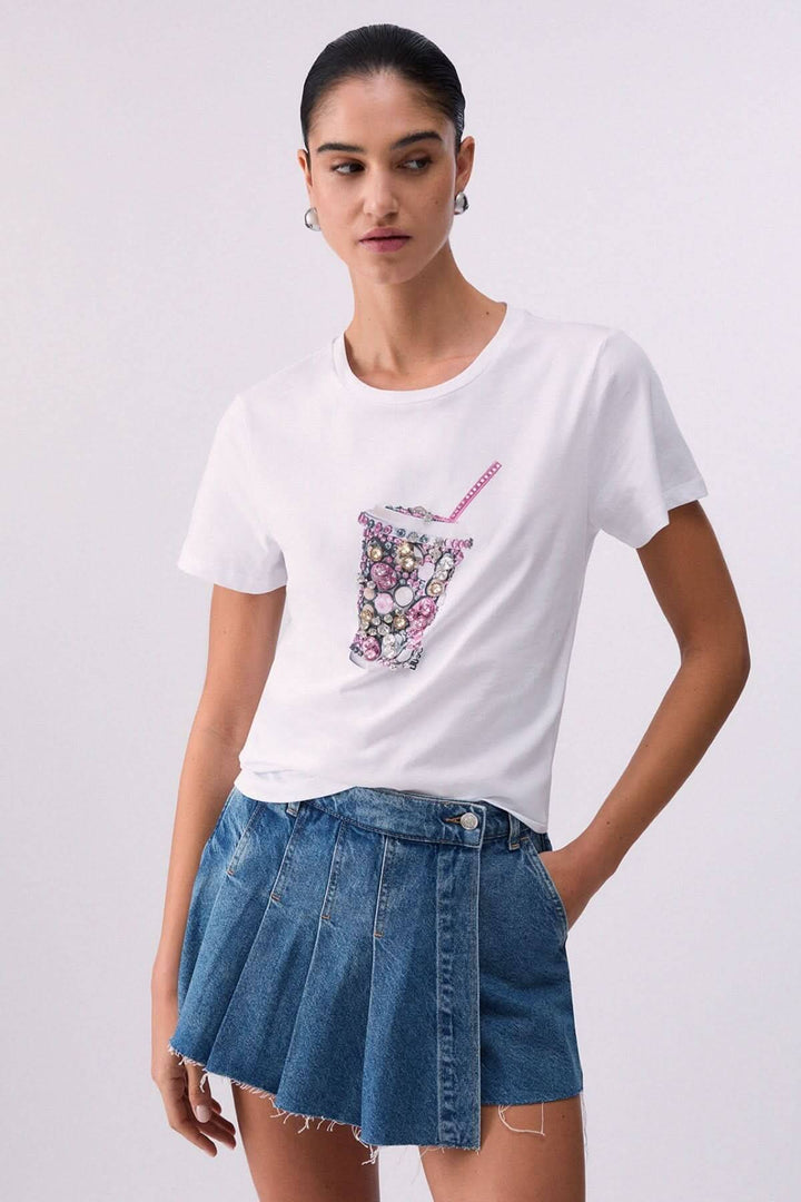 Femme portant un T-shirt avec motif décoratif et une jupe en jean, vue de face.