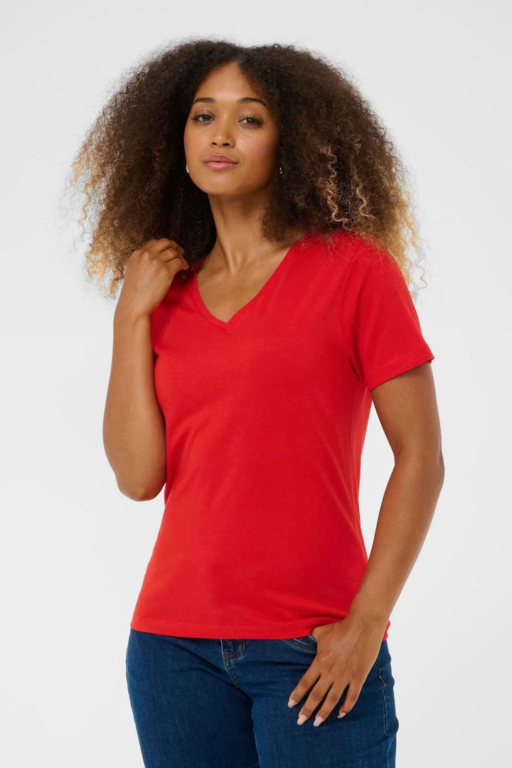 Femme portant un T-shirt col en V rouge, confortable et stylé.