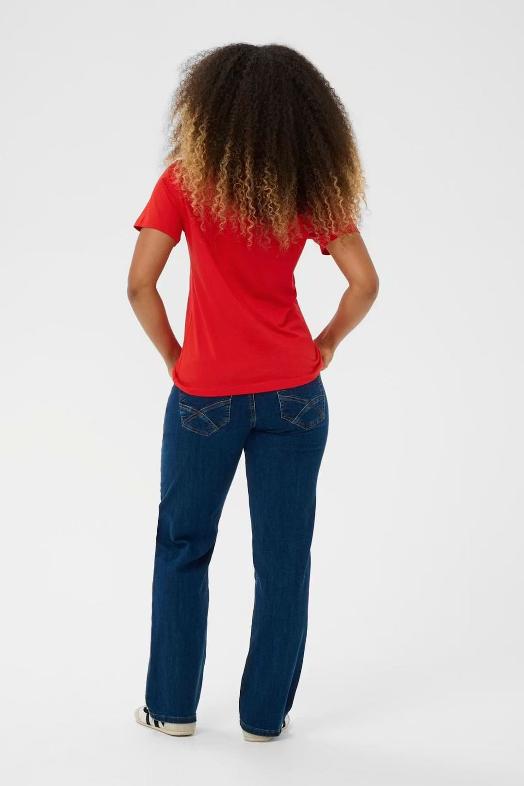 T-shirt col en V rouge, silhouette épurée, porté avec un jean pour un style décontracté et confortable.