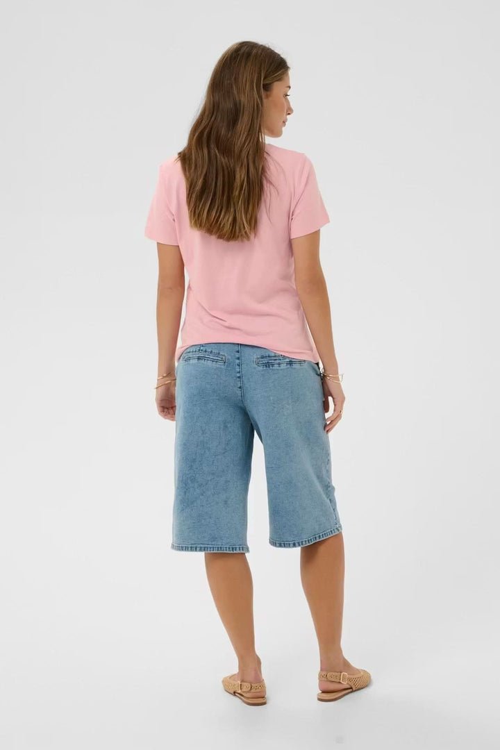 Femme portant un t-shirt col en V rose avec un jean pour un look décontracté. Idéal pour un style quotidien confortable.