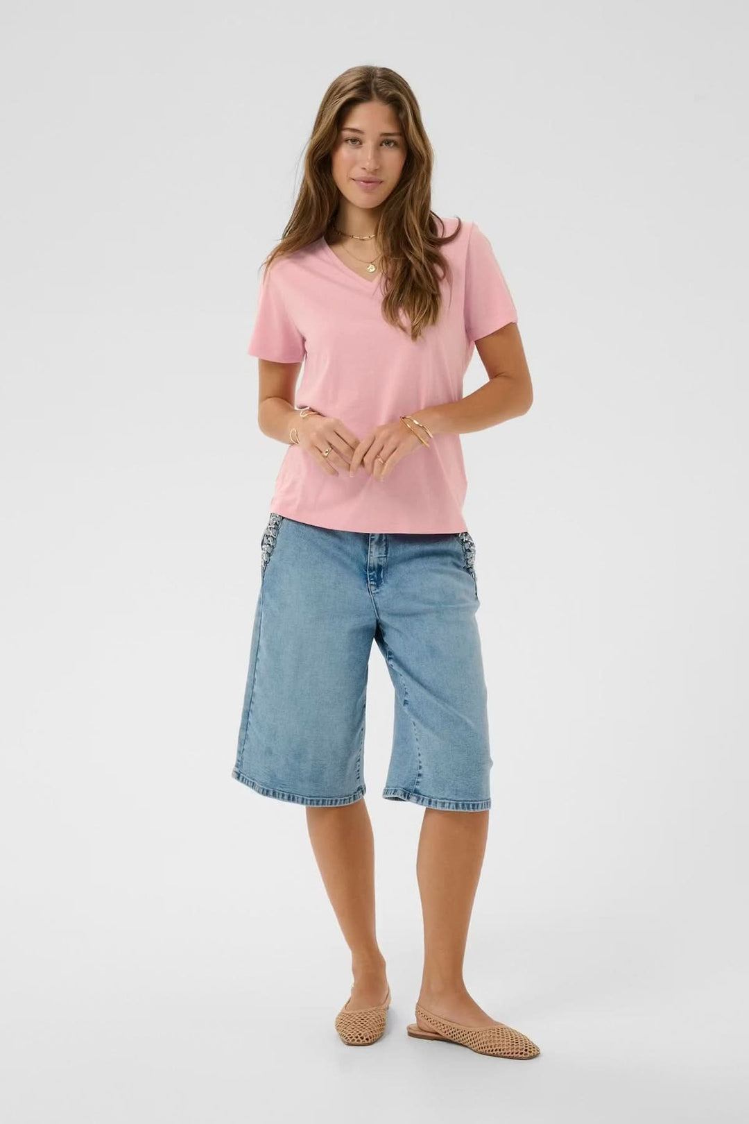 Femme portant un T-shirt col en V rose avec un jean, offrant un confort et une coupe flatteuse au quotidien.