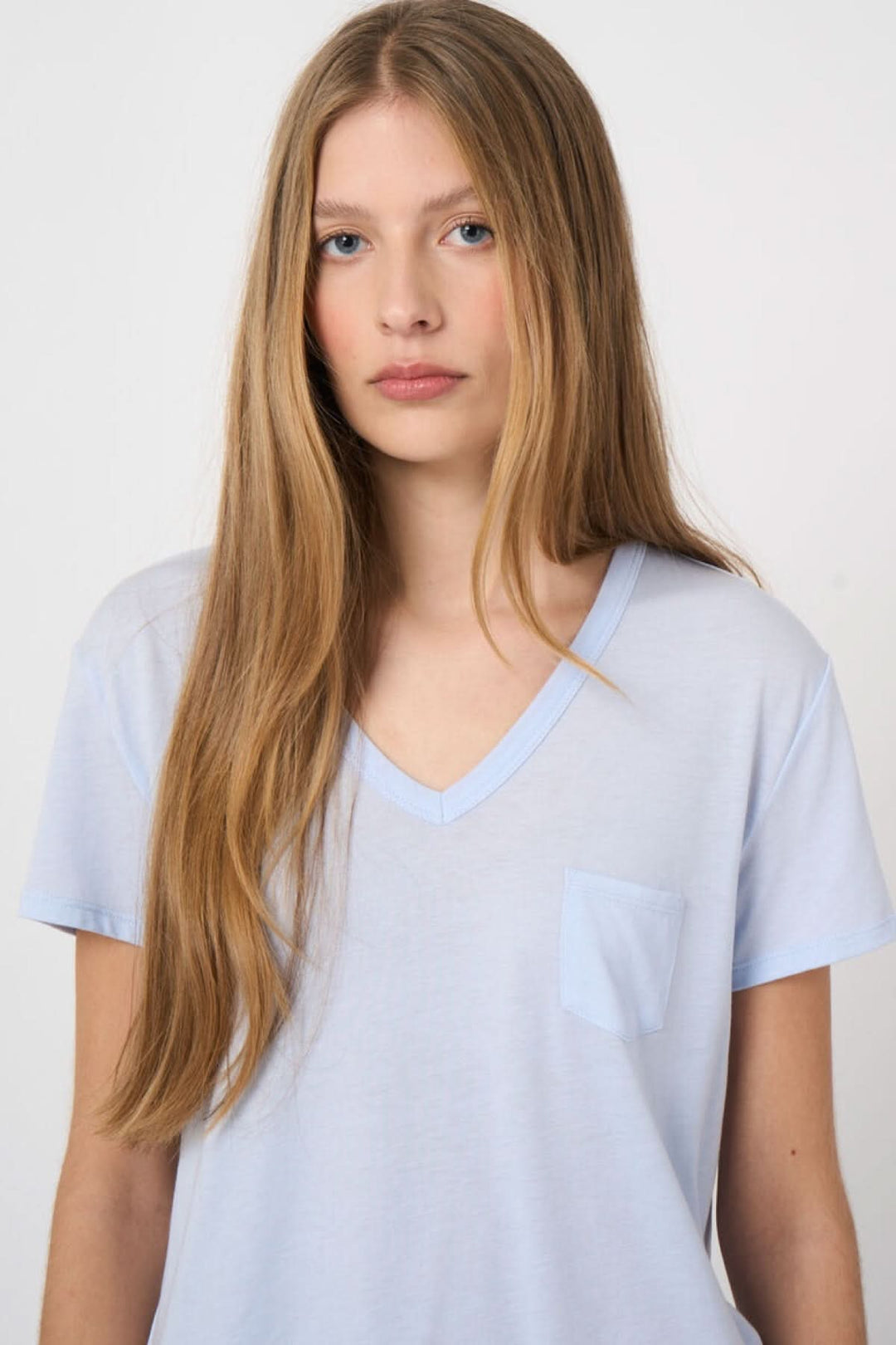 Jeune femme portant un T-shirt col en V manches courtes en tissu doux, idéal pour un style décontracté et confortable.