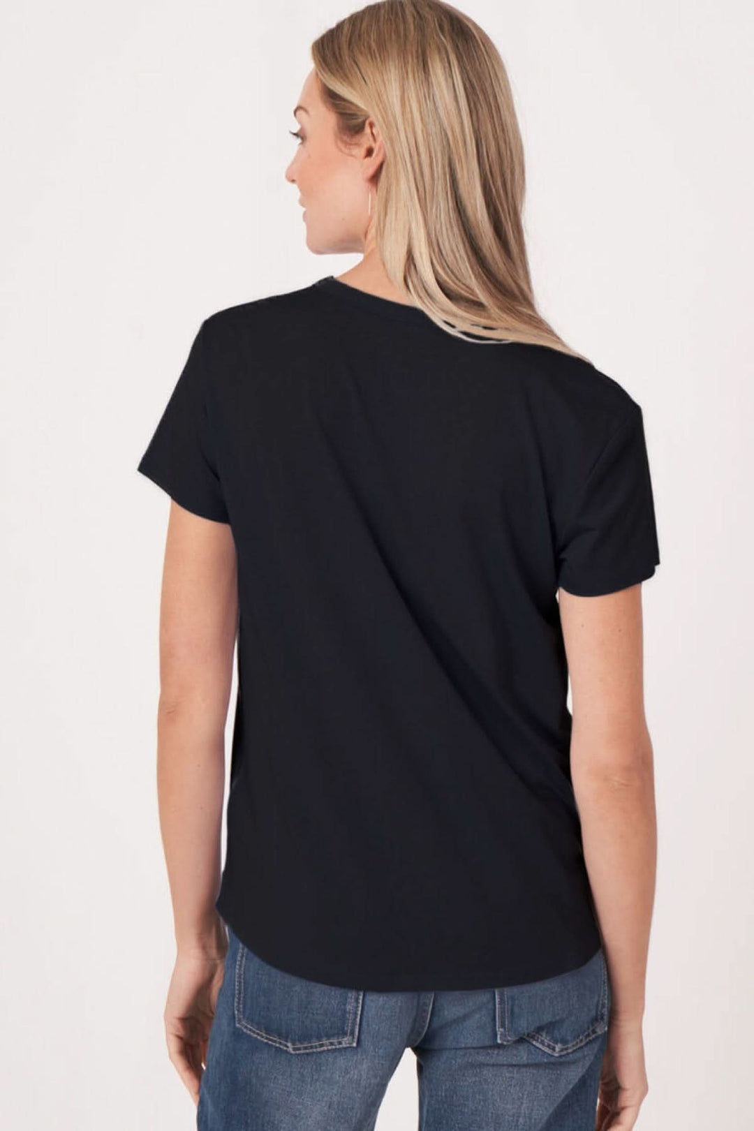 Femme portant un T-shirt col en V manches courtes noir, vue de dos, look décontracté et moderne.