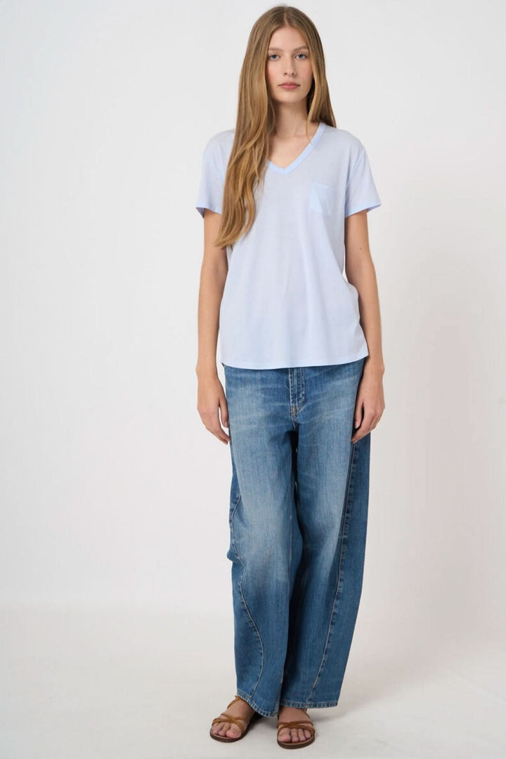 Femme portant un T-shirt col en V manches courtes, coupe moderne et épurée pour un style décontracté, tissu doux et confortable.