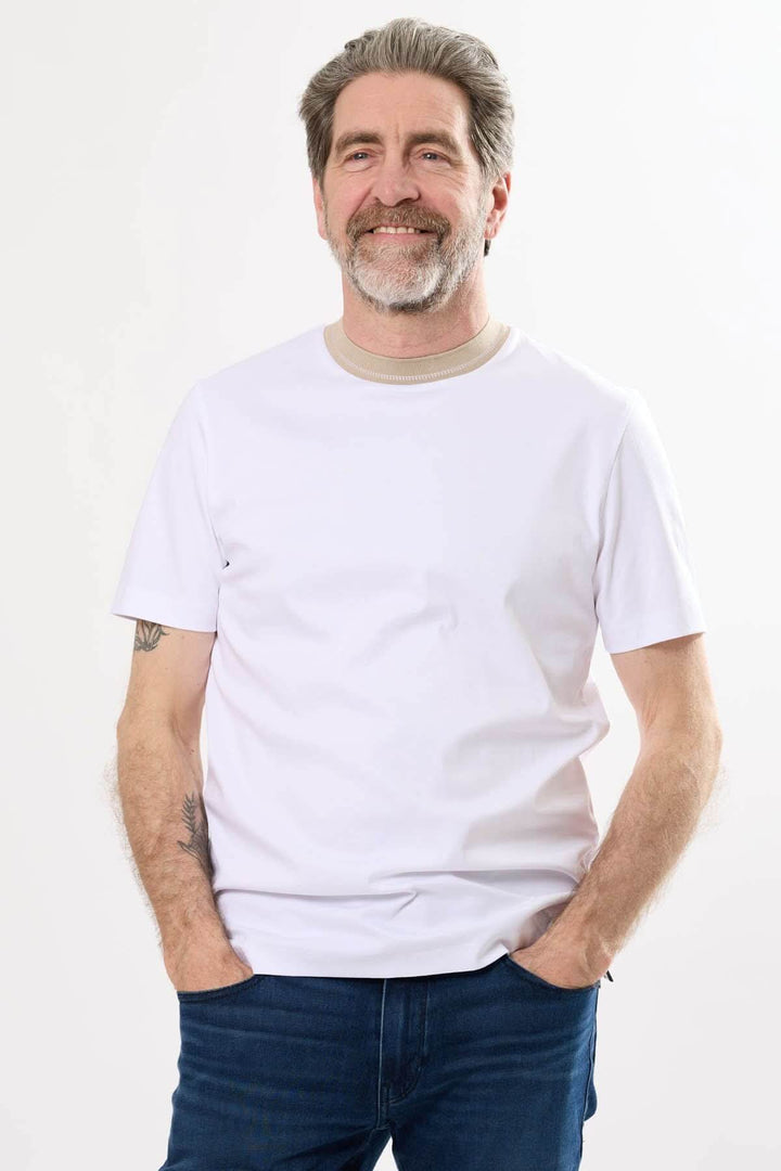 T-shirt blanc à col rayé porté par un homme souriant, parfait pour des tenues décontractées.