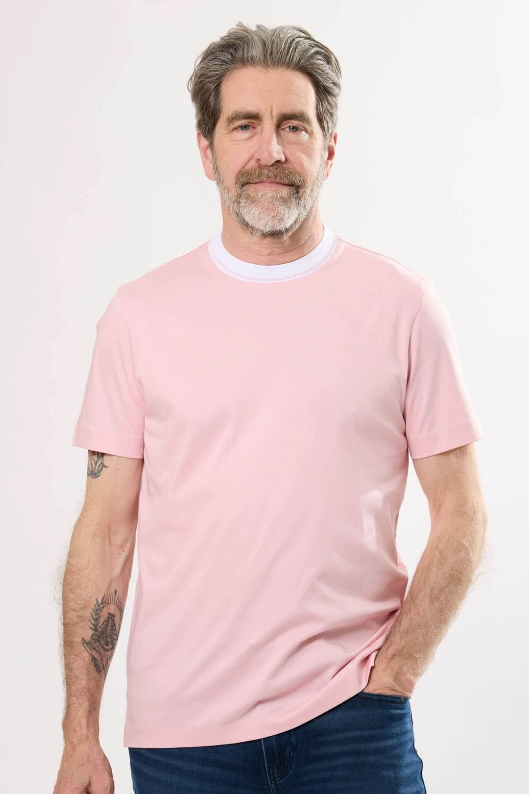 Homme portant un t-shirt à col rayé rose, combinaison idéale pour un look décontracté et moderne.