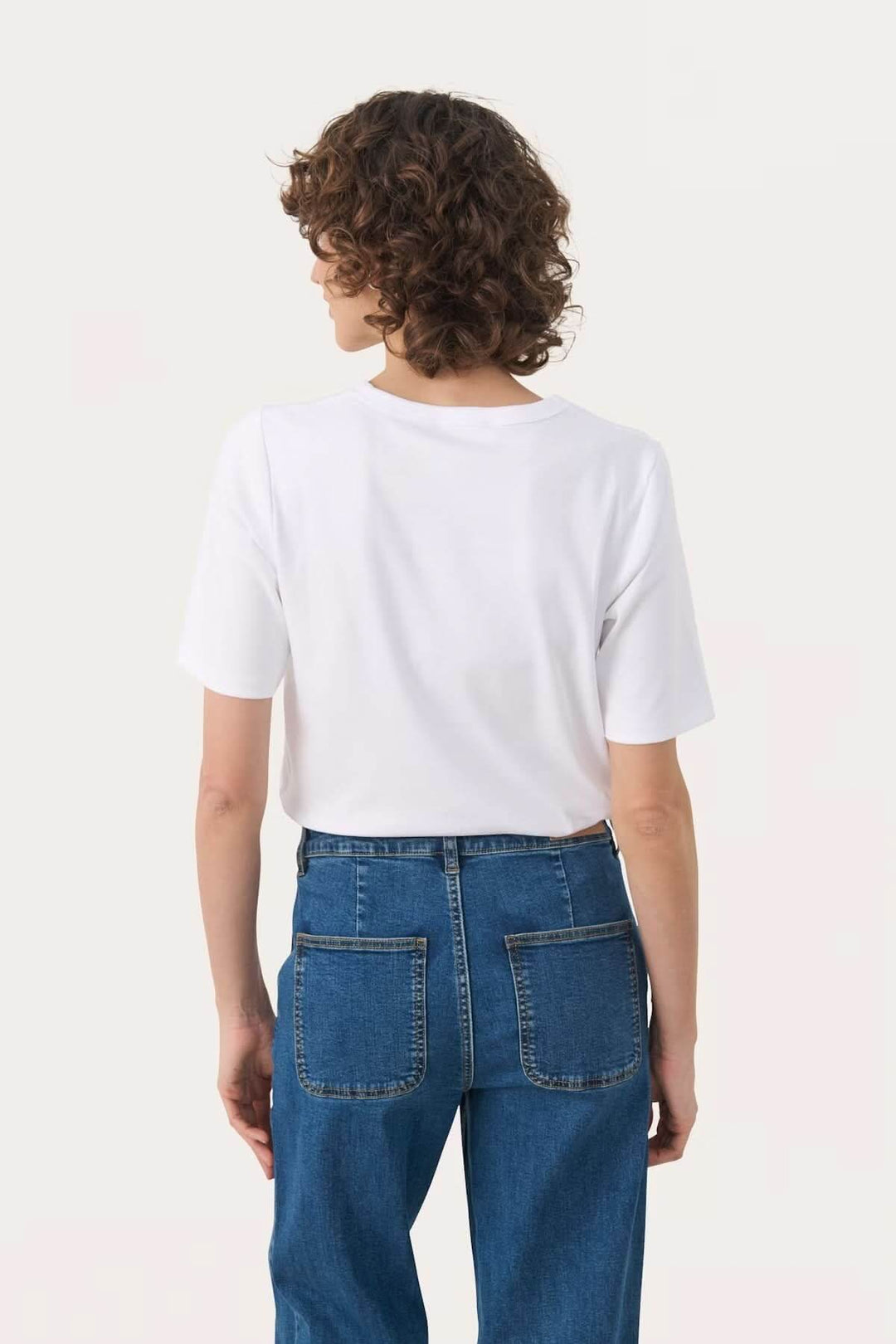 T-shirt à col rond blanc porté avec un jean, vue de dos, mettant en avant le confort et le style décontracté.