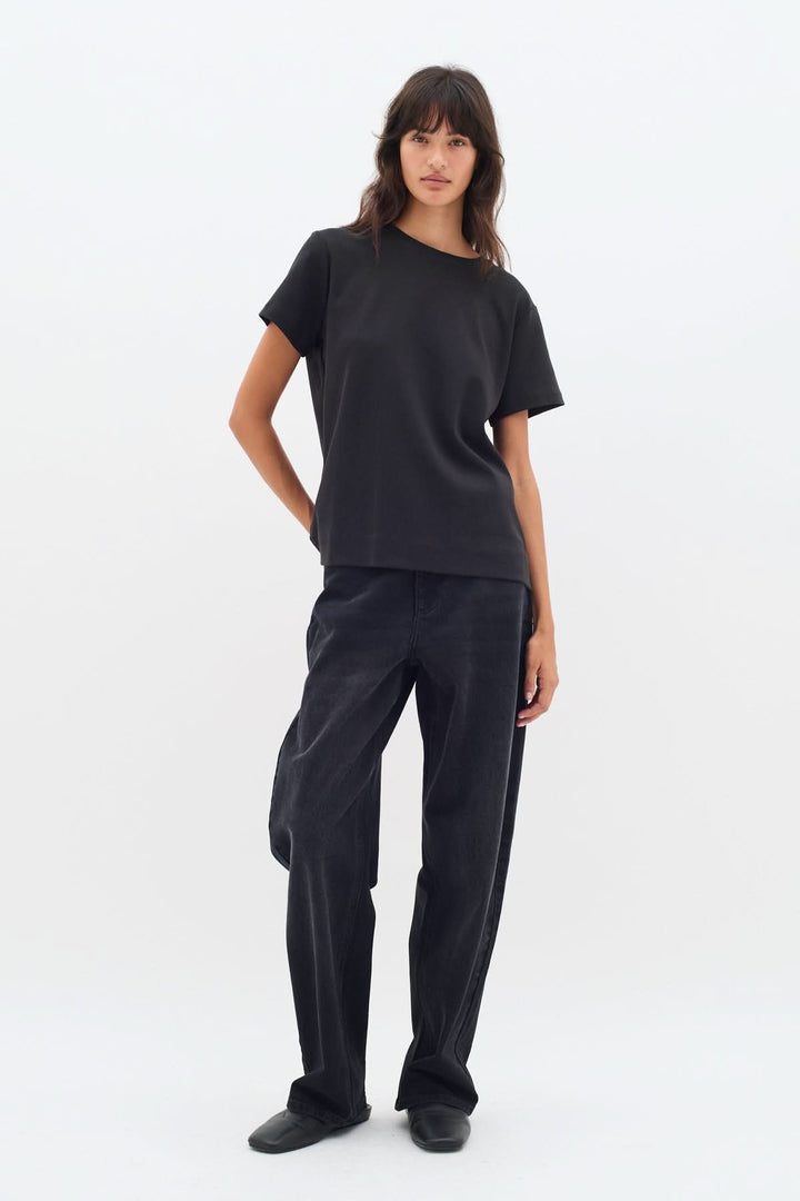 T-shirt col rond Luke noir porté avec un pantalon noir, alliant confort et style, coupe légèrement ample.