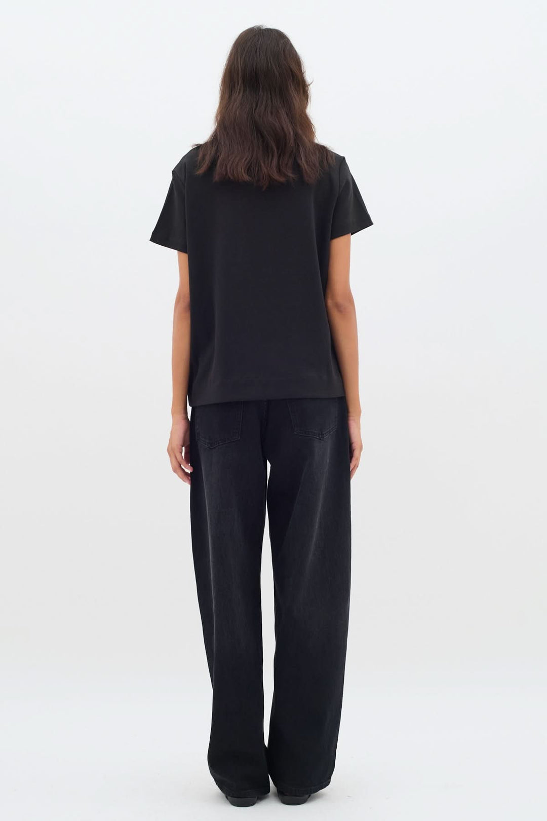 Femme portant un t-shirt noir col rond avec une coupe légèrement ample vue de dos.