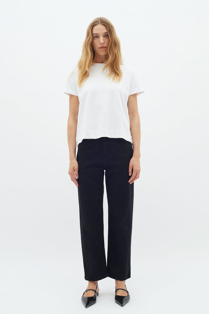 Femme portant un t-shirt col rond Luke, silhouette moderne avec pantalon noir, style décontracté.