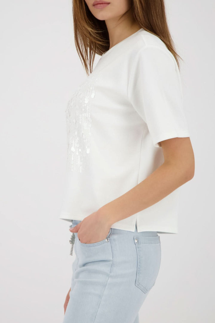 T-shirt à empiècement pailleté sur femme portant un jean clair, style moderne et féminin, détail brillant ton sur ton au centre.
