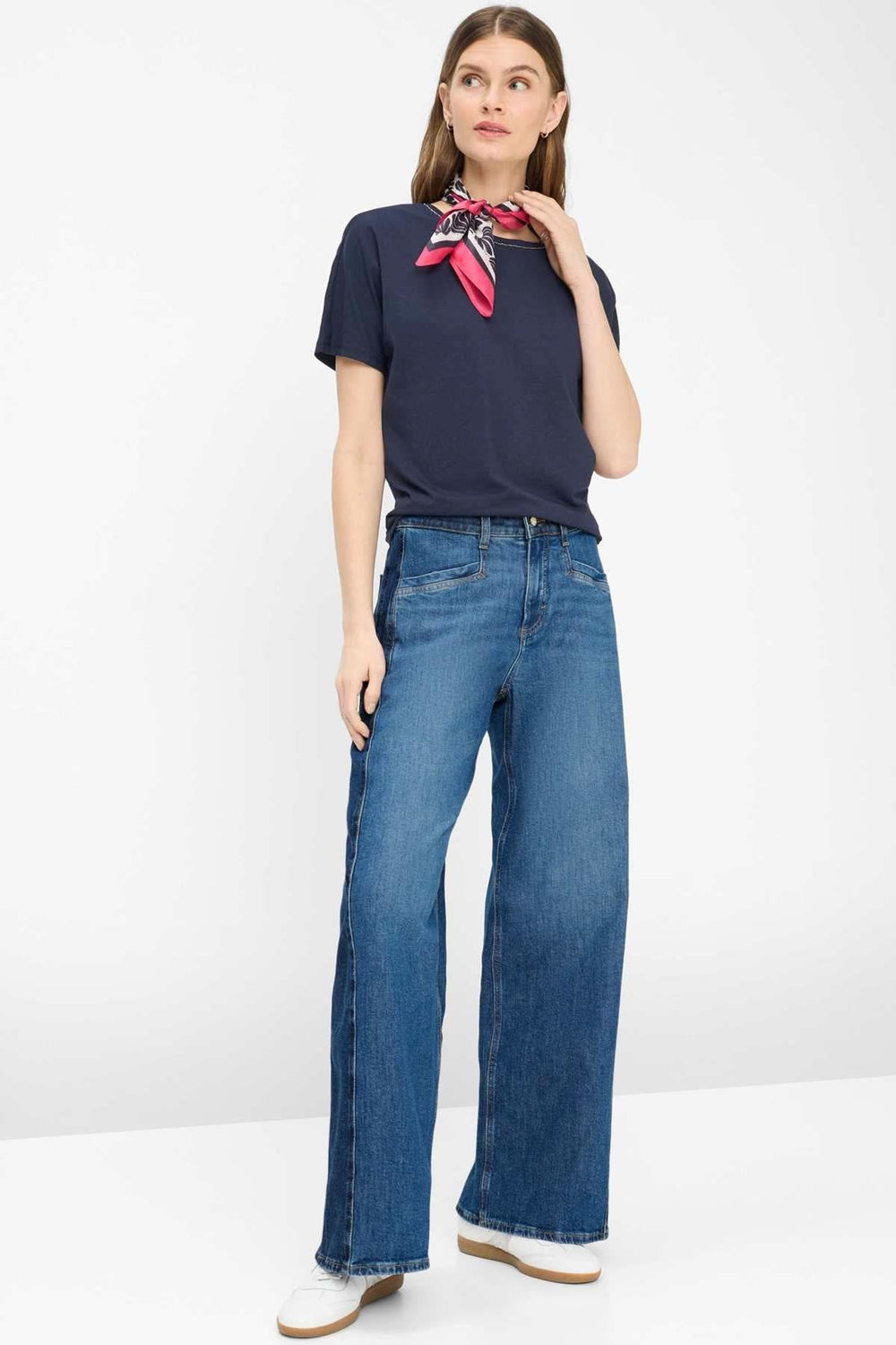 Femme portant un T-shirt encolure perlée Caelen avec des jeans évasés, illustrant l'élégance et le confort du quotidien.