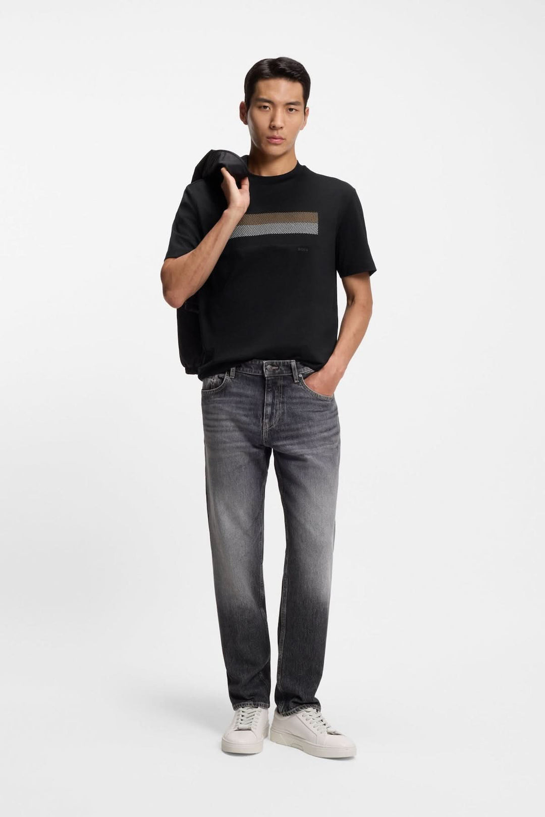 Homme portant un T-shirt à imprimé graphique minimaliste avec jean et basket blanches, style décontracté et moderne.