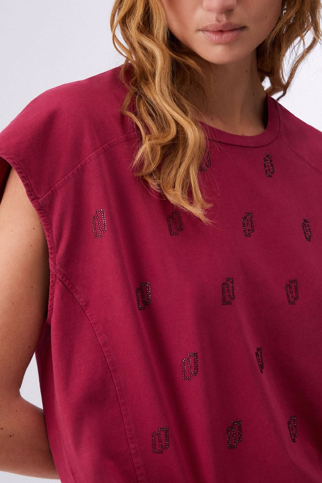 Femme portant un t-shirt imprimé à manches courtes bordeaux avec motif discret, tissu léger et confortable.