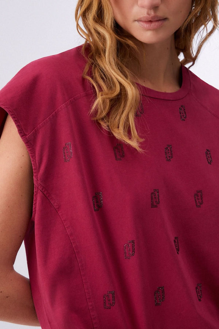 Femme portant un t-shirt imprimé à manches courtes bordeaux avec motif discret, tissu léger et confortable.
