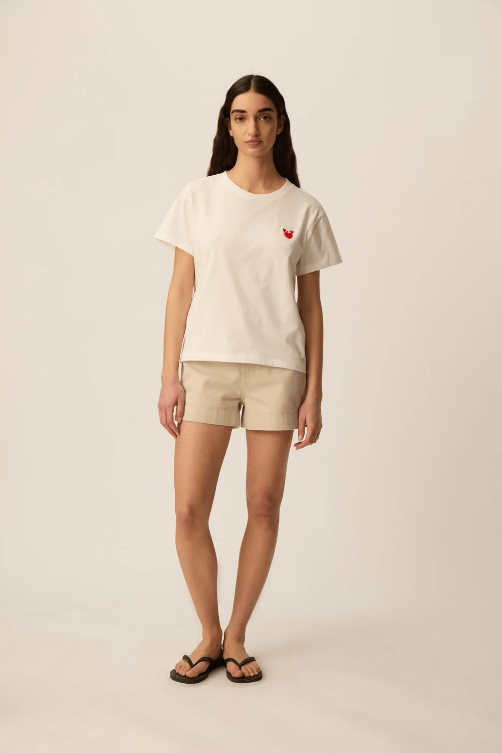 Femme portant un T-shirt à manches courtes col rond coupe classique avec détail discret sur la poitrine.