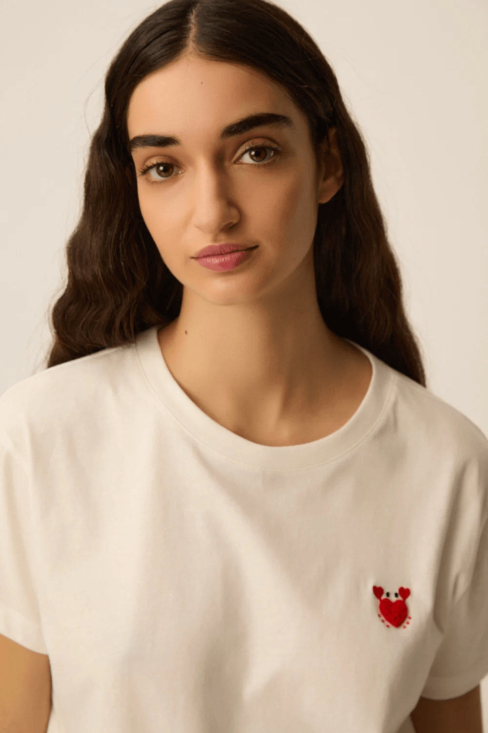 Femme portant un T-shirt à manches courtes col rond coupe classique avec détail discret à la poitrine, tissu doux et confortable.
