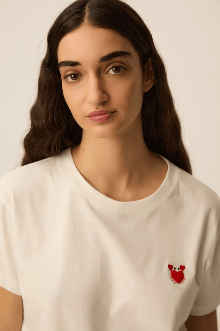 Femme portant un T-shirt à manches courtes col rond coupe classique avec détail discret à la poitrine, tissu doux et confortable.
