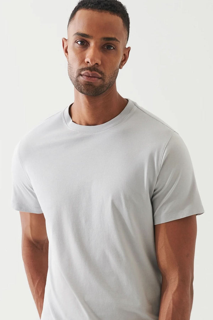 Homme portant un T-shirt minimaliste gris à col rond, style épuré et confortable.